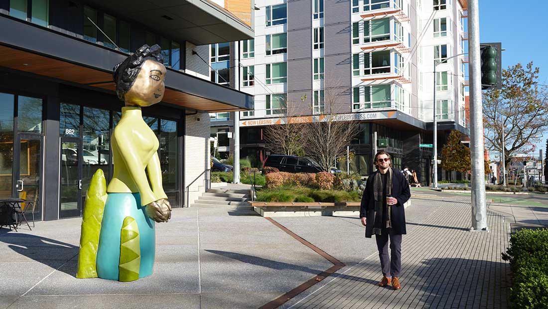 person walking by sculpture